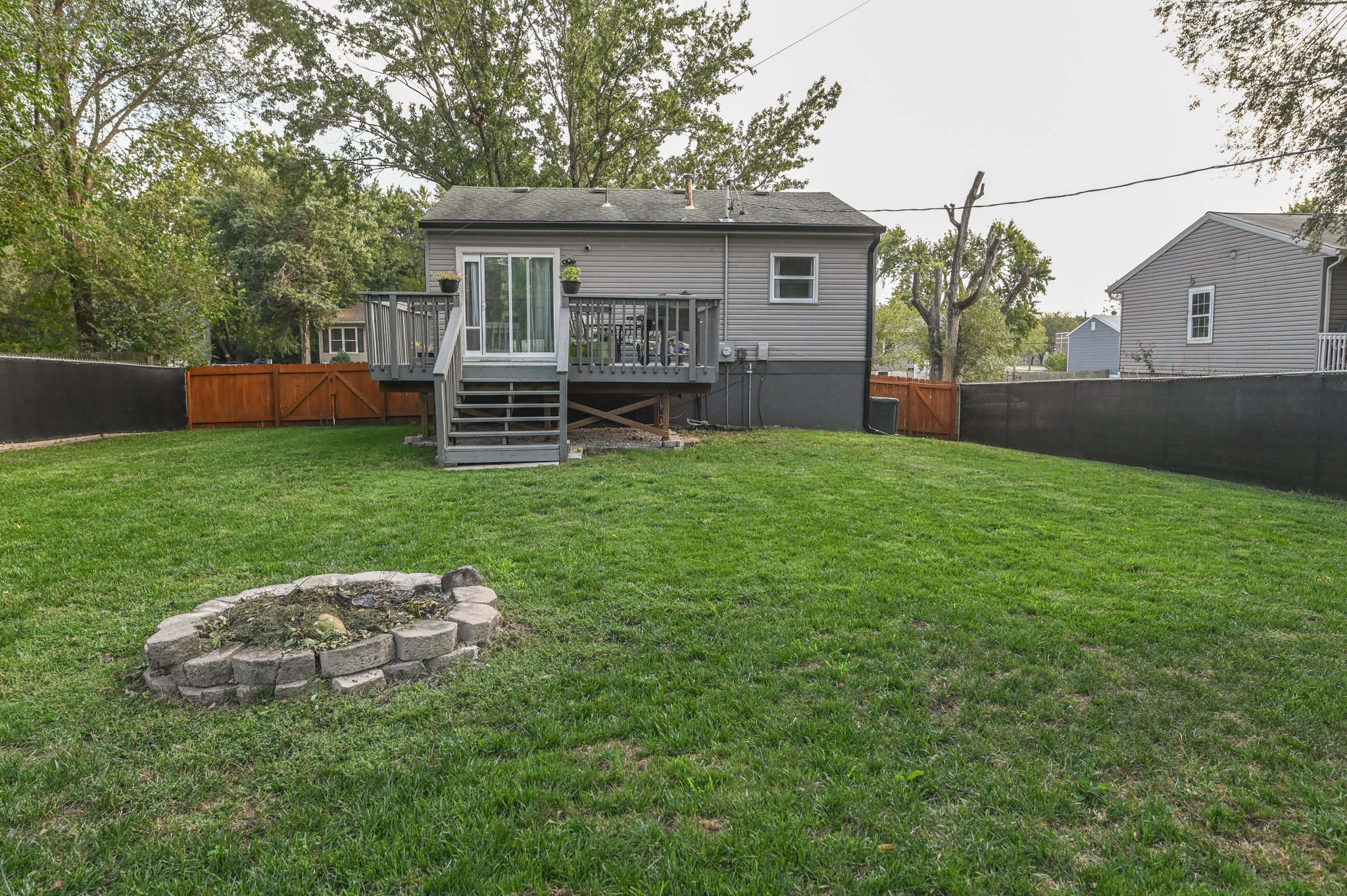 Oversized deck and fenced backyard with fire pit