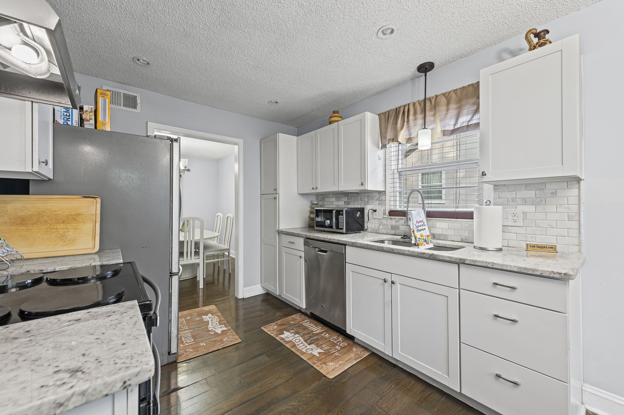 Updated kitchen with white cabinets, stainless steel, and tile backsplash