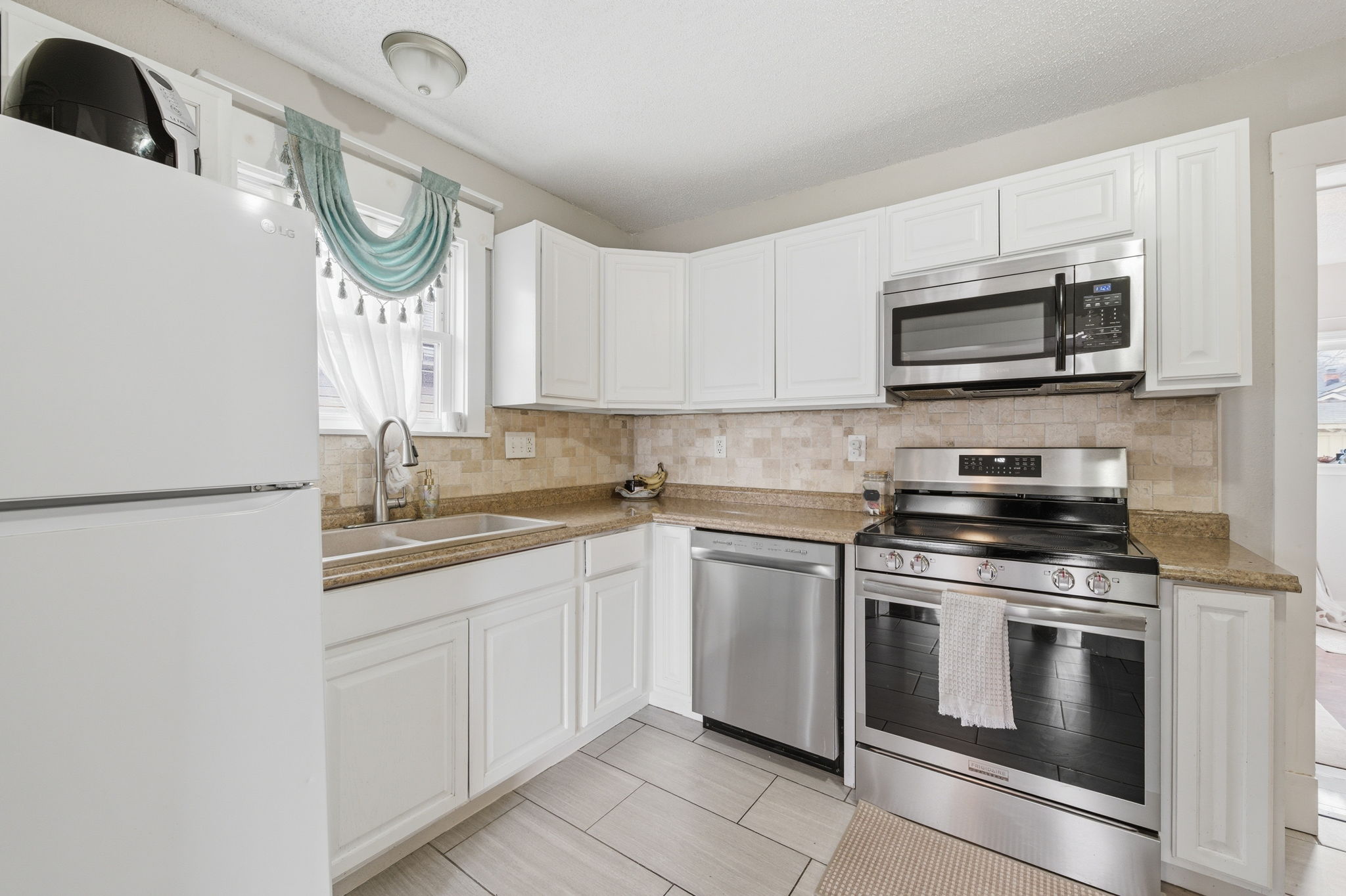Updated eat-in kitchen with white cabinets and stainless appliances