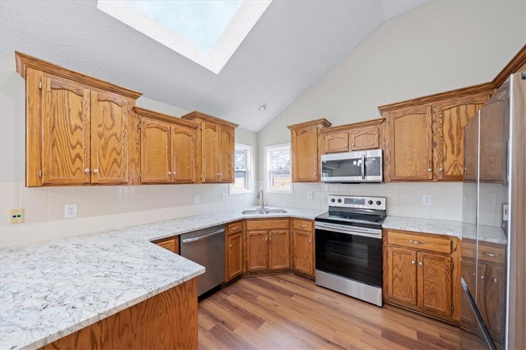 Skylit kitchen with center island and newer stainless appliances
