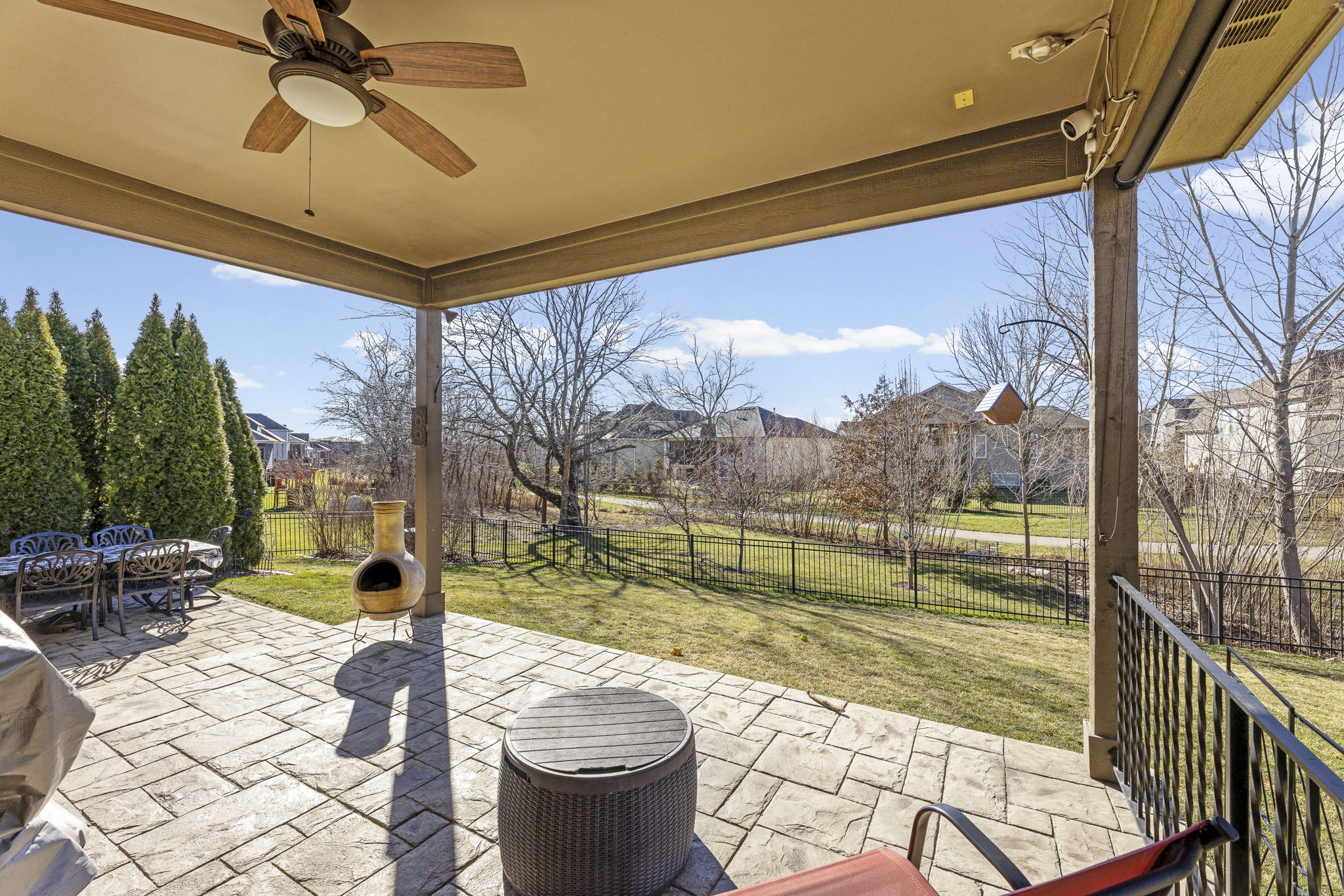 Covered stamped-concrete patio overlooking the fenced backyard